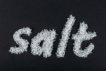 top view of word salt made of salt crystals on black background