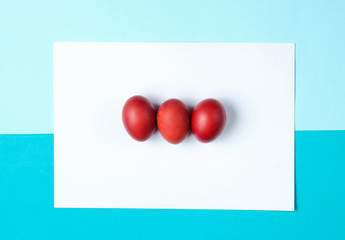 Red chicken eggs on color paper background. Minimalistic Easter concept