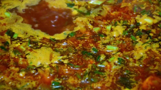 Cooking healthy food. Soup with greens boils on the stove.