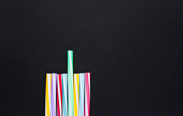 Lot of multi-colored cocktail tubes on black background. Top view