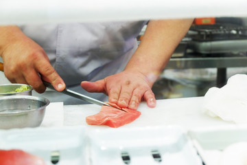 Japanese Chef Preparing Sushi.  He prepares sushi, known as nigiri, for dinner. This traditional Japanese food is being prepared on a wooden platter. stock photo