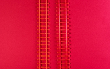 Toy railway rails on a red background. Top view