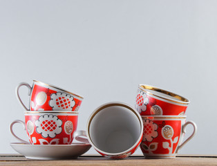 Many antique ceramic cups on a wooden table against a white wall