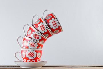Stack of antique ceramic cups on a wooden table against a white wall