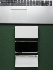 The concept of unboxing, techno blogging. Box with new smartphone, laptop on green background. Top...
