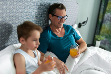 Father in glasses and son watching tv in room
