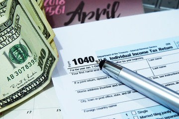 Tax Season: 1040 U.S. Individual Income Tax Return Form Horizontal top right view of an office laptop background with a metallic pen preparation on taxation. - image