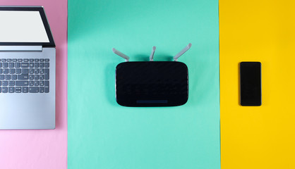 Wi fi router, smartphone, laptop on colored background. Modern gadgets. Top view
