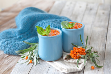 Bright sea buckthorn tea in blue ceramic mugs on wooden table. Natural medicine vitamin drink