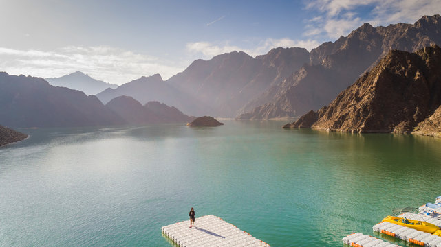 Aerial view of a woman standing in front of the Hatta Lake in Dubai, U.A.E.