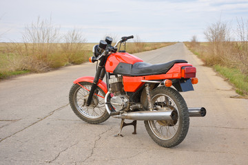 Red motorcycle stands on the empty road