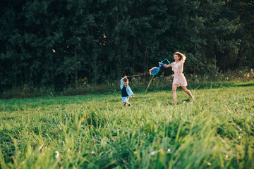 Happy family mother and child son launch a kite on nature at sunset