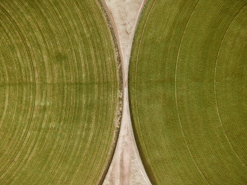 Aerial view of a car driving in between two agricultural circles in the middle of the Saih Al Salam Desert in Dubai, U.A.E.