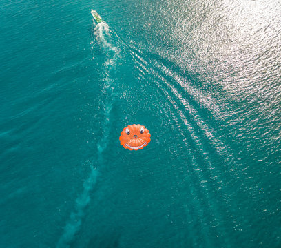 Aerial view of parachute with smiley face being pulled by boat, Santorini, Greece.