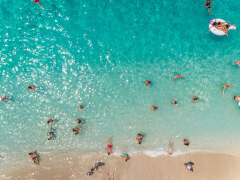 NIKITAS, GREECE - 13 JULY 2018: Aerial view of vacationers enjoying swimming in the sea on sandy beach.