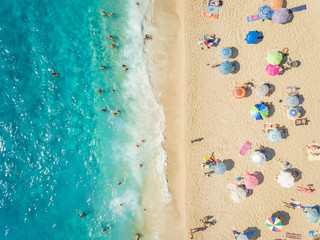 Aerial view of people relaxing under colorful parasols on beach