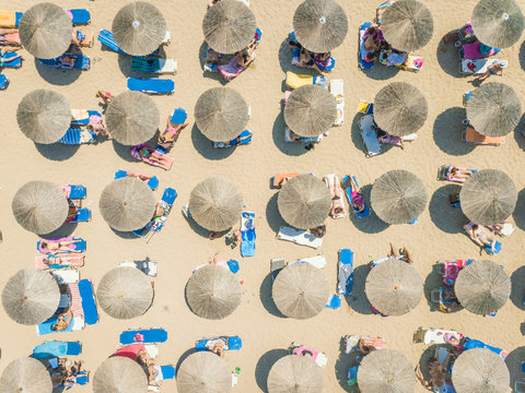 Aerial view of people relaxing under straw parasols on beach