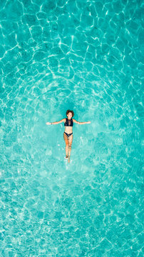 Aerial view of a woman floating in the sea of Ithaca island.
