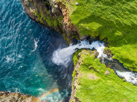 Aerial view above of M˙lafossur waterfall ending on North Atlantic sea, Faroe island.