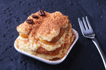 Piece of appetizing homemade tiramisu cake on plate in close up.