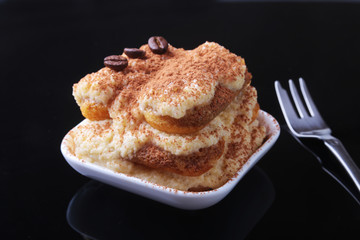 Piece of appetizing homemade tiramisu cake on plate in close up.