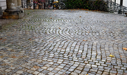 Antique pavement background. Wet paved square in Berlin city of Germany. Wet cobblestone sidewalk. Stone texture. Fall backdrop. Autumn rainy weather background.