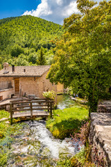 The small village of Rasiglia, crossed by many streams and waterfalls, fed by the Menotre river. A sluice regulates the flow of water. A wooden bridge. Old brick houses. Foligno, Umbria.