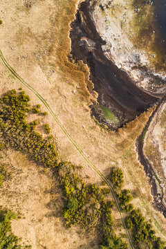 Abstract aerial view of empty dirt road next to algae beach on coastline in Estonia
