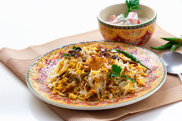Halal Indian chicken Biryani served with yogurt tomato raita over white background. Selective focus.