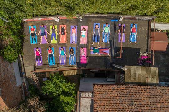 Aerial view of a group of people doing yoga on a terrace surrounded by trees in town
