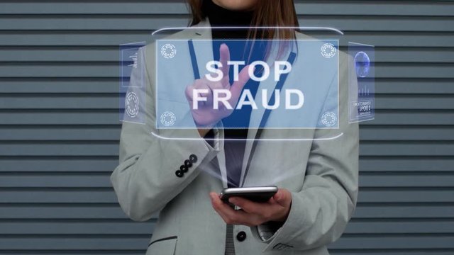 Unrecognizable business woman, interacts with a HUD hologram with text stop fraud. Girl in a business suit uses the technology of the future mobile screen against the background of a striped wall