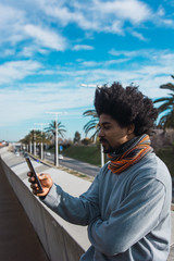 Portrait of black man with afro hair while looking at his smartphone