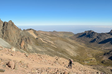 Fototapeta na wymiar A hiker against a mountain range in the volcanic landscapes of Mount Kenya, Kenya