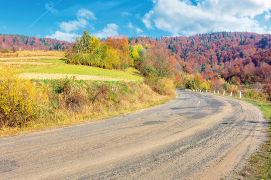 old cracked country road in autumn. traditional carpathian countryside. warm sunny day. trees in colorful foliage. green grass on the rural fields. loacrion Uzhok serpentine, ukraine