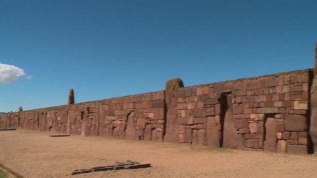 Medium close-up low-angle panning panoramic view of the ancient Kalassaya stone wall, and site visitors,  La Paz, Bolivia, 