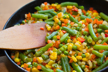 Colorful mix of vegetables is fried in a frying pan close up. Food