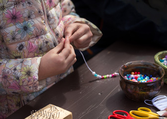 Fototapeta na wymiar Girl making necklace from beads