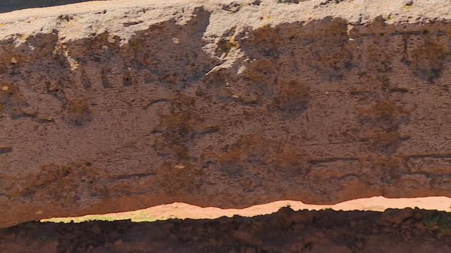 Extreme close-up high angle panning shot of ancient engravings on curved stone at Tiwanaku Ruins, Al Paz, Bolivia
