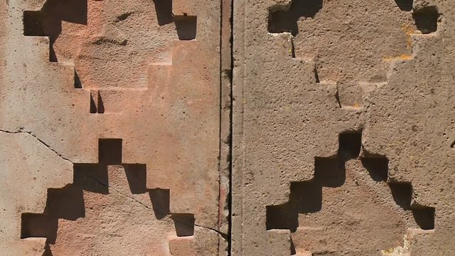 Extreme close-up front tilting shot of stone ruins of Pumapunku with precise geometric patterns chiselled on their surfaces, La Paz, Bolivia