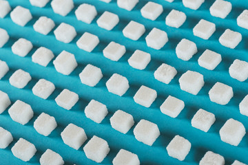 white sugar cubes arranged in rows on blue surface