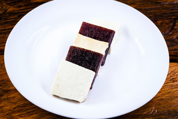 Brazilian dessert known as Romeo and Juliet. Sliced ​​cheese with pieces of guava on white plate.