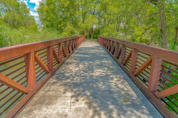 Fototapeta na wymiar Bridge with rusty metal guardrails over a lake viewed on a sunny day