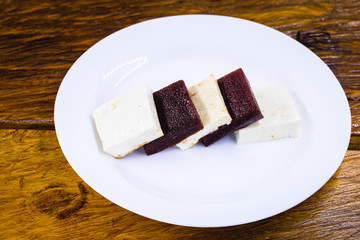 Brazilian dessert known as Romeo and Juliet. Sliced ​​cheese with pieces of guava on white plate.