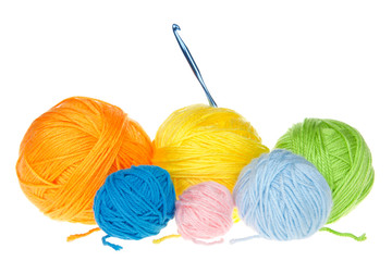 Many colorful balls of yarn in various sizes isolated on white with single crochet hook.