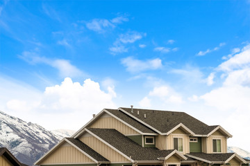 House exterior with view of the dark pitched roof against a cloudy blue sky