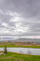 Silvery lake overlooking distant mountains under sky filled with gray clouds