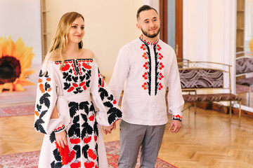 Obraz premium girl and guy in embroidered clothes hold hands in a beautiful ha