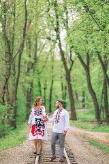 Obraz premium Newlyweds in embroidered clothes are walking along the railway i