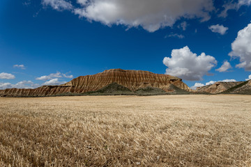 une montagne rouge devant des champs de céréale