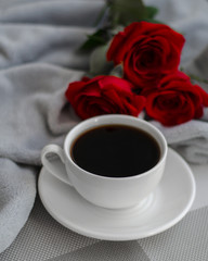 Cup of black coffe and red roses on grey background